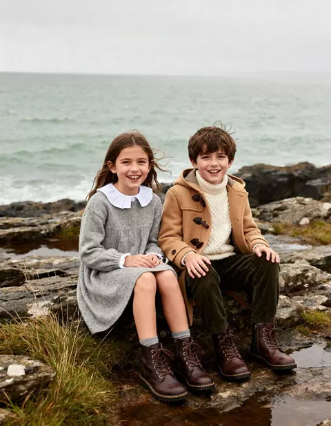 Niña y niño con ropa de invierno sentados en las rocas
